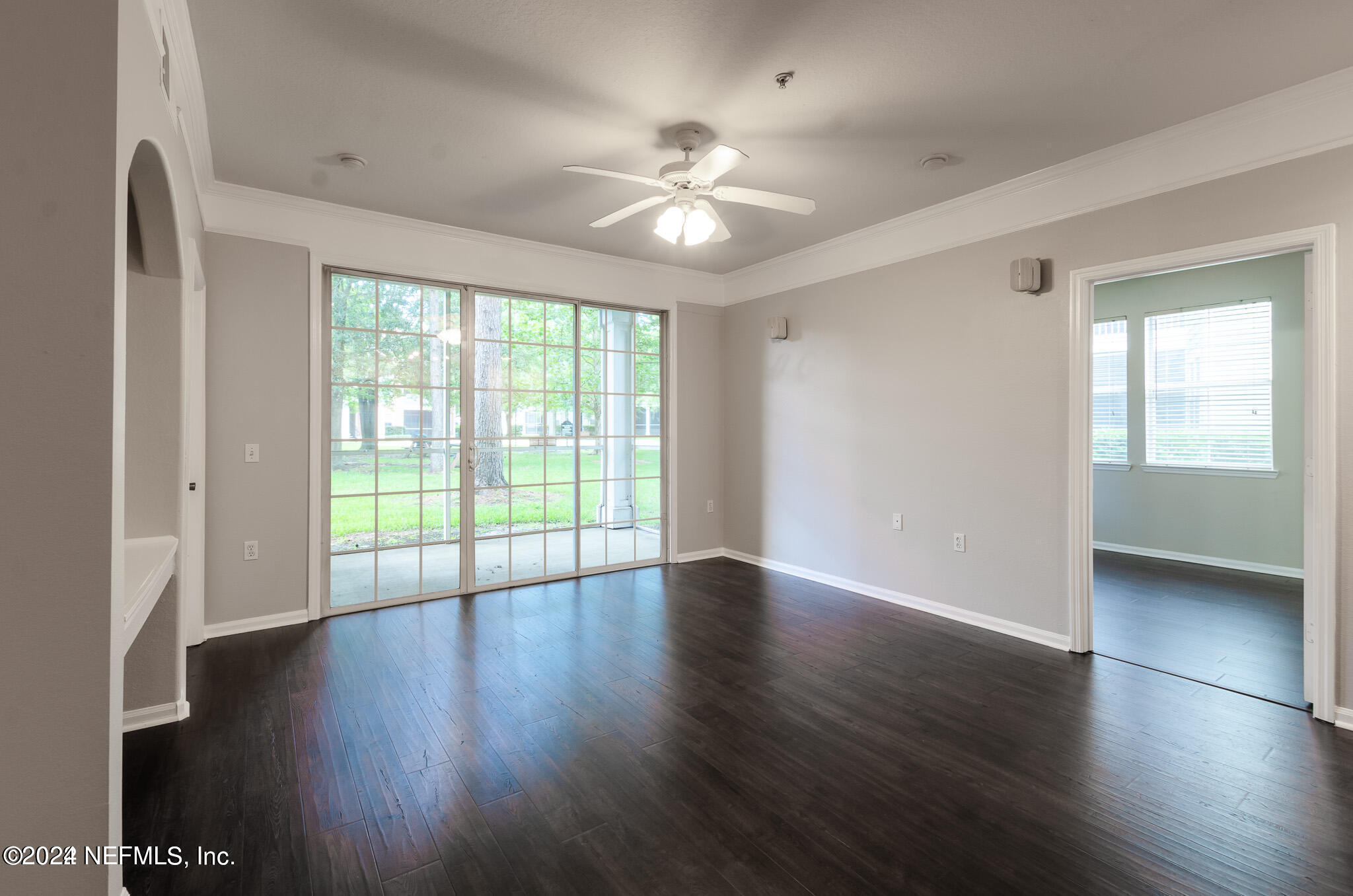 a view of an empty room with wooden floor and a window