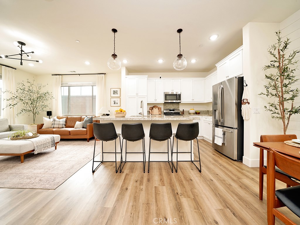 a living room with stainless steel appliances kitchen island granite countertop furniture and a wooden floor