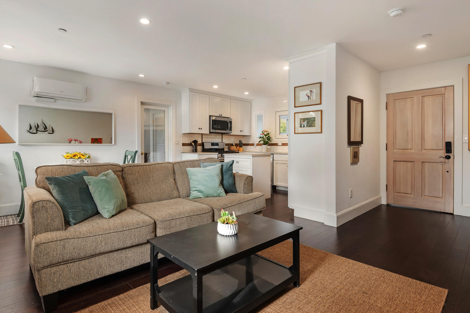 a living room with stainless steel appliances furniture and a wooden floor