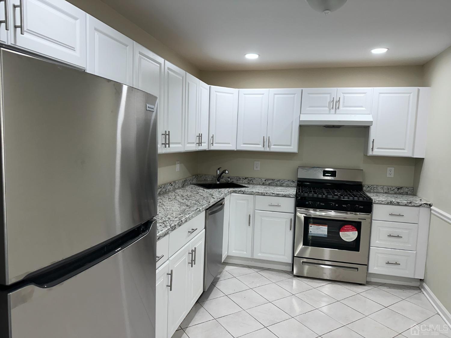 a kitchen with granite countertop white cabinets and stainless steel appliances