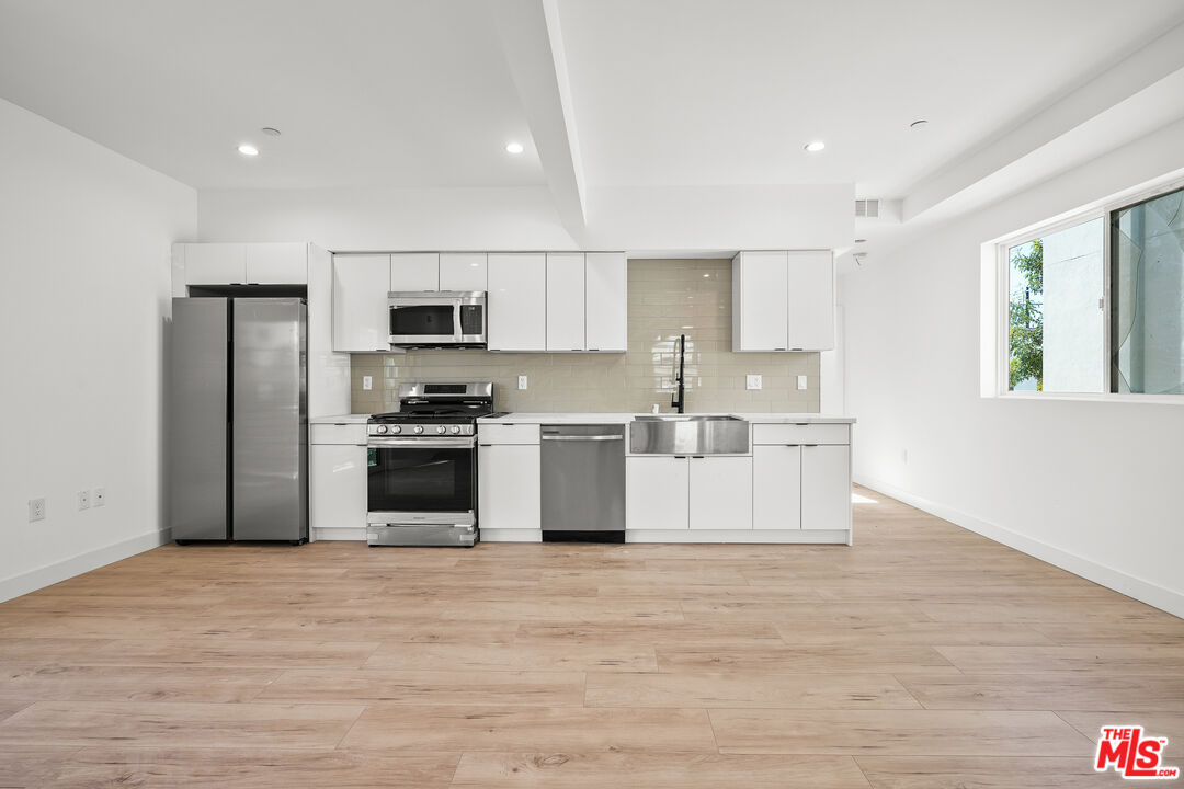 a kitchen with stainless steel appliances a refrigerator sink and microwave