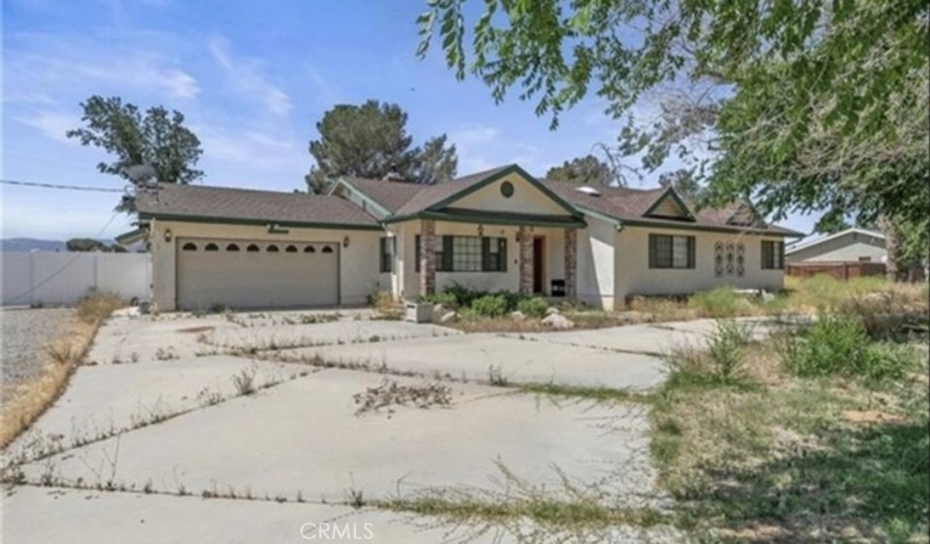 a view of a house with a dry tree and wooden fence