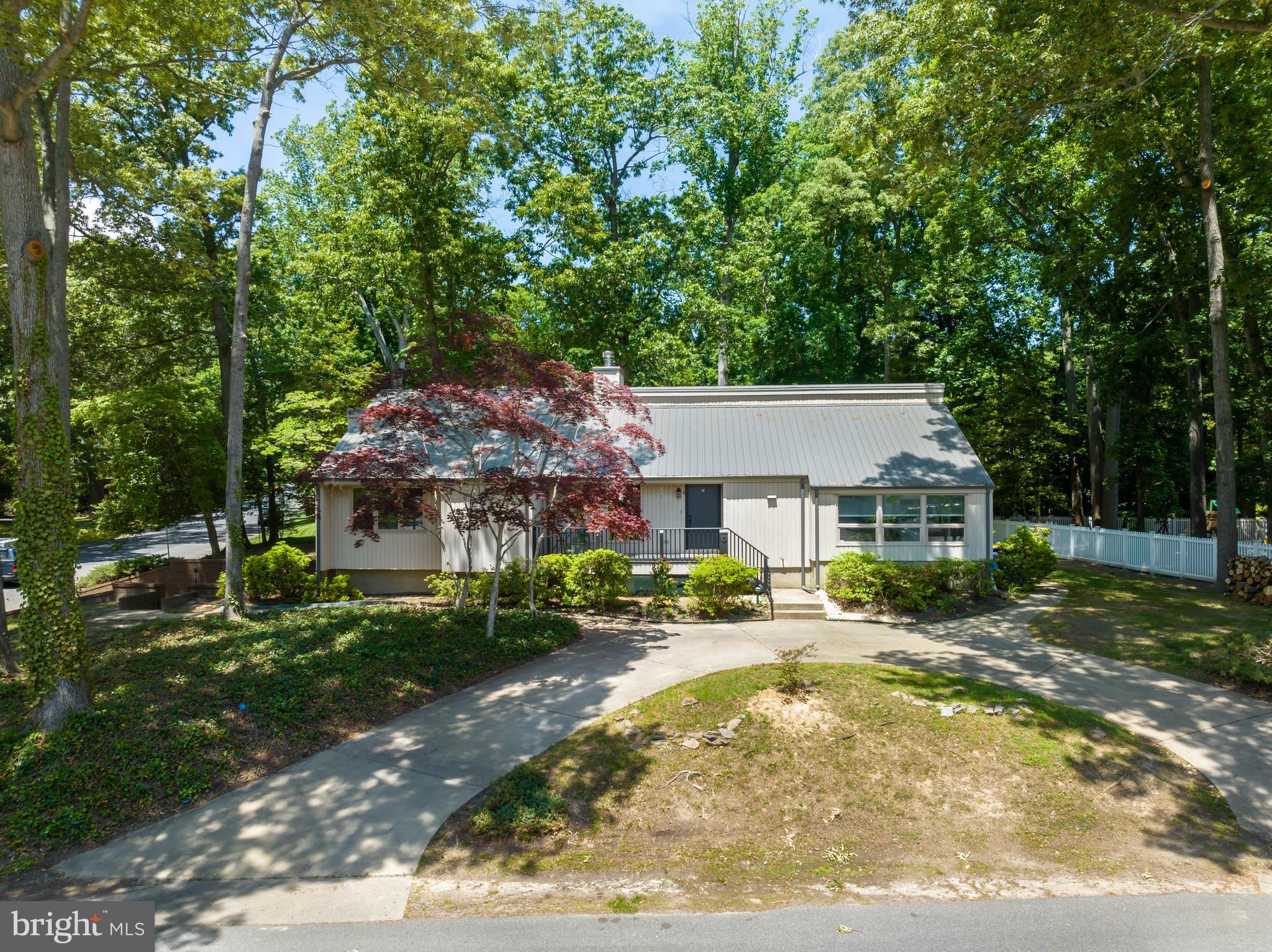 a view of a house with a big yard plants and large trees