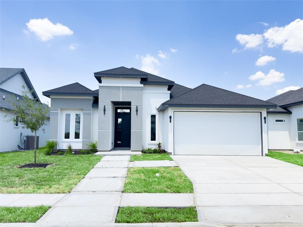 Prairie-style house featuring a front lawn, central AC, and a garage