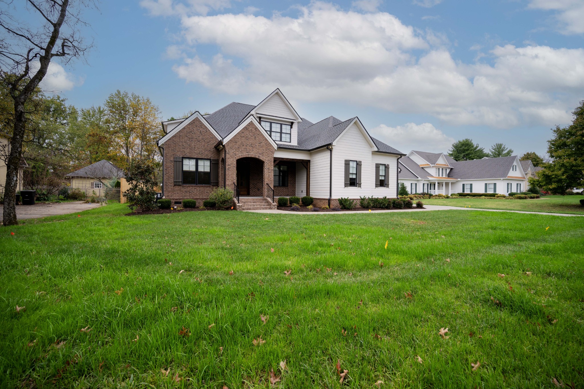 a front view of a house with a garden and trees