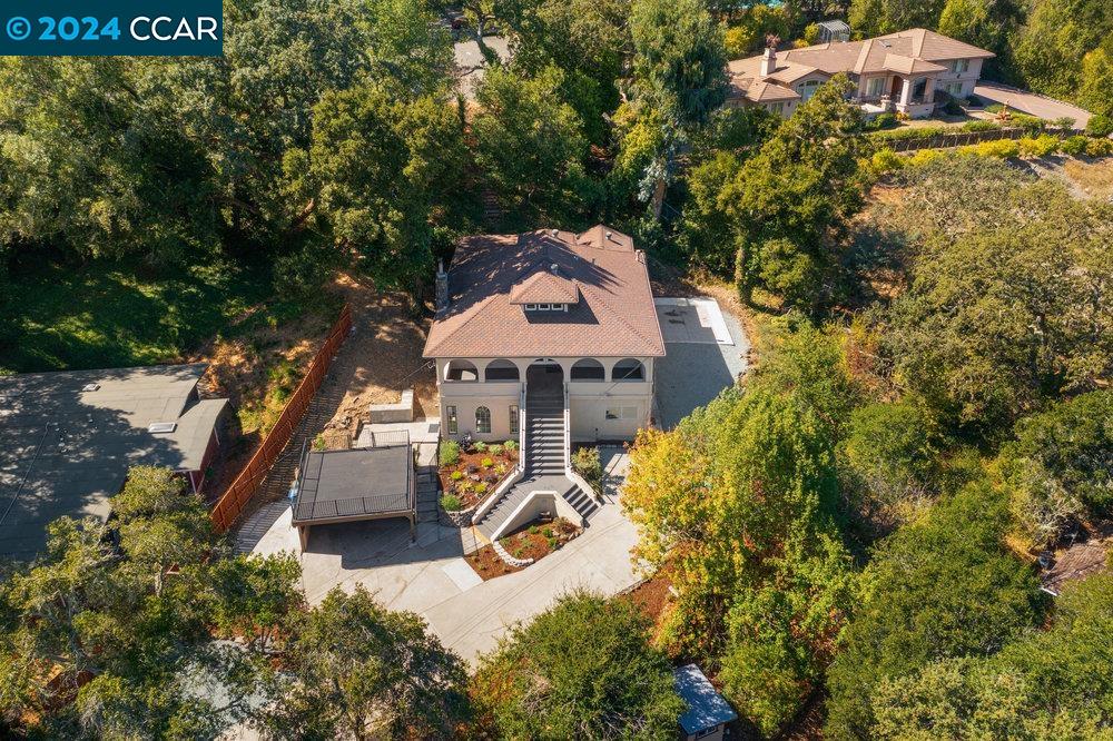 an aerial view of a house with swimming pool and large trees