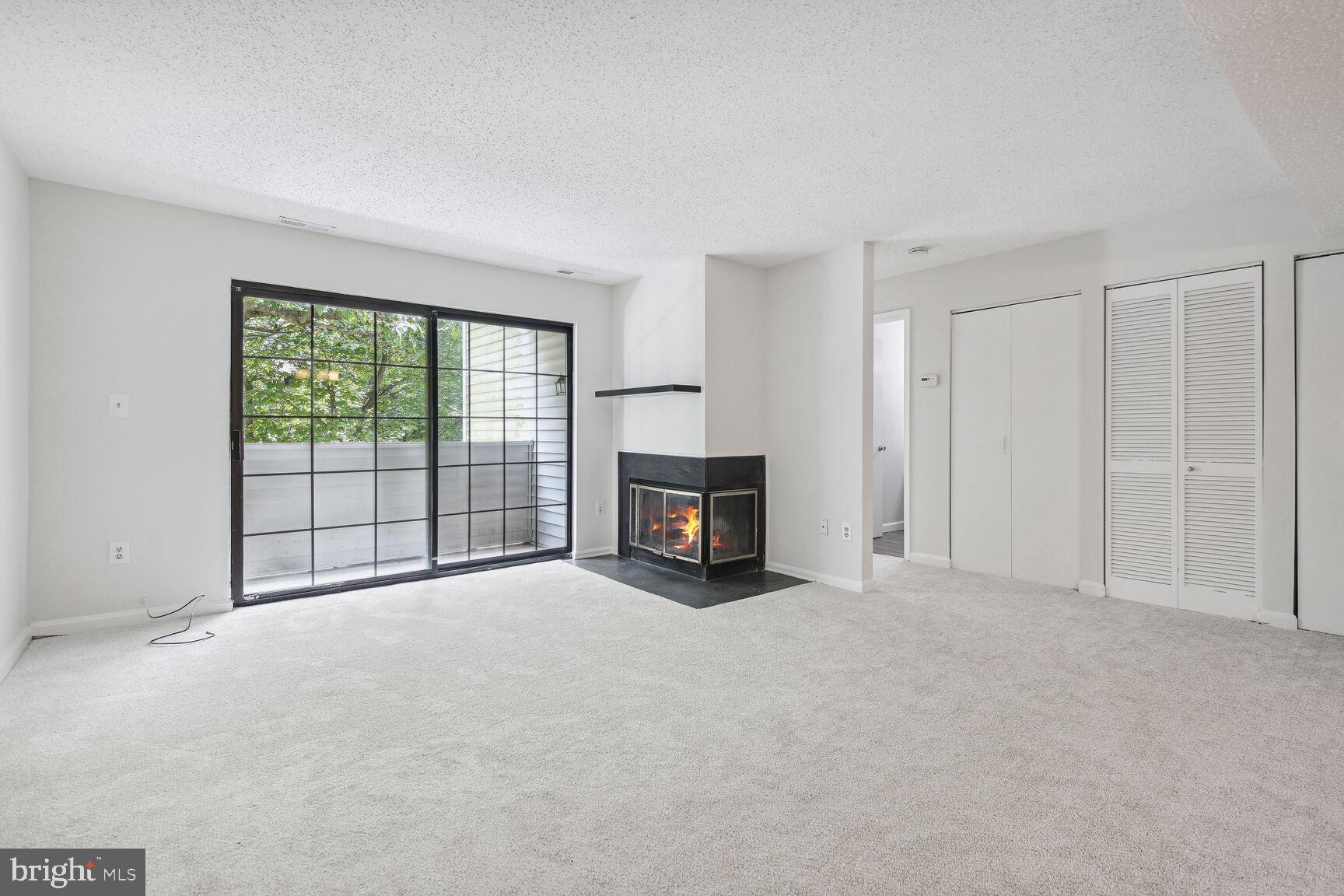 a view of an empty room with a fireplace and a window