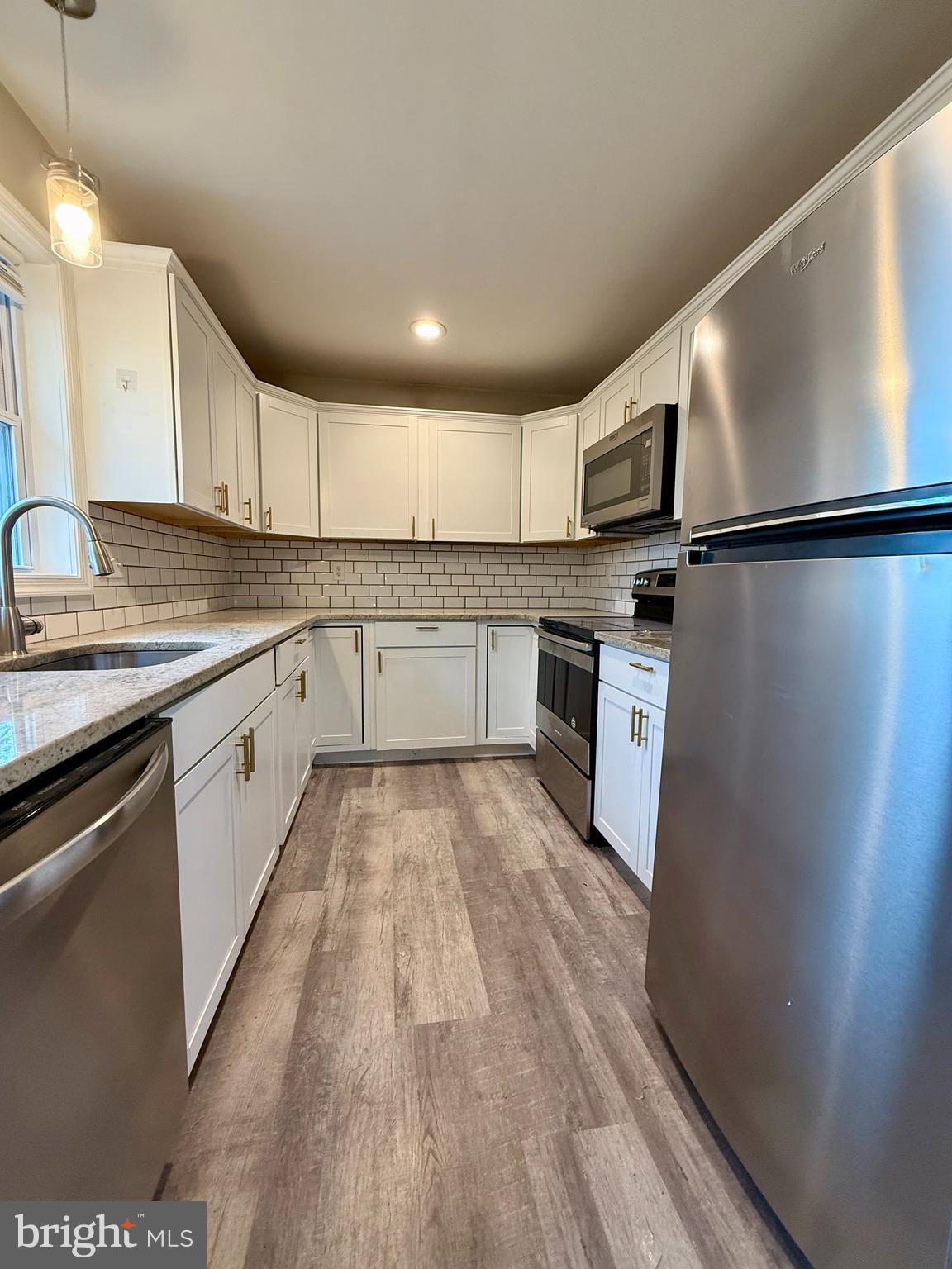 a kitchen with stainless steel appliances granite countertop a sink refrigerator and cabinets