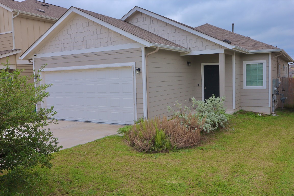 a view of a house with brick walls and a yard with plants