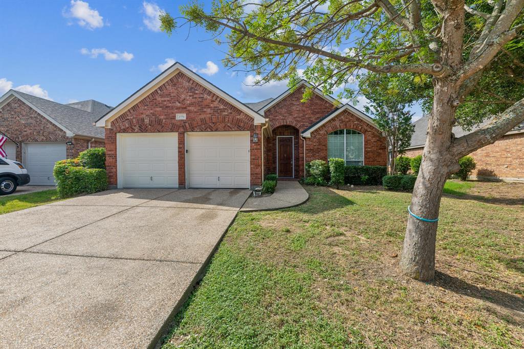 a front view of a house with a yard and large tree