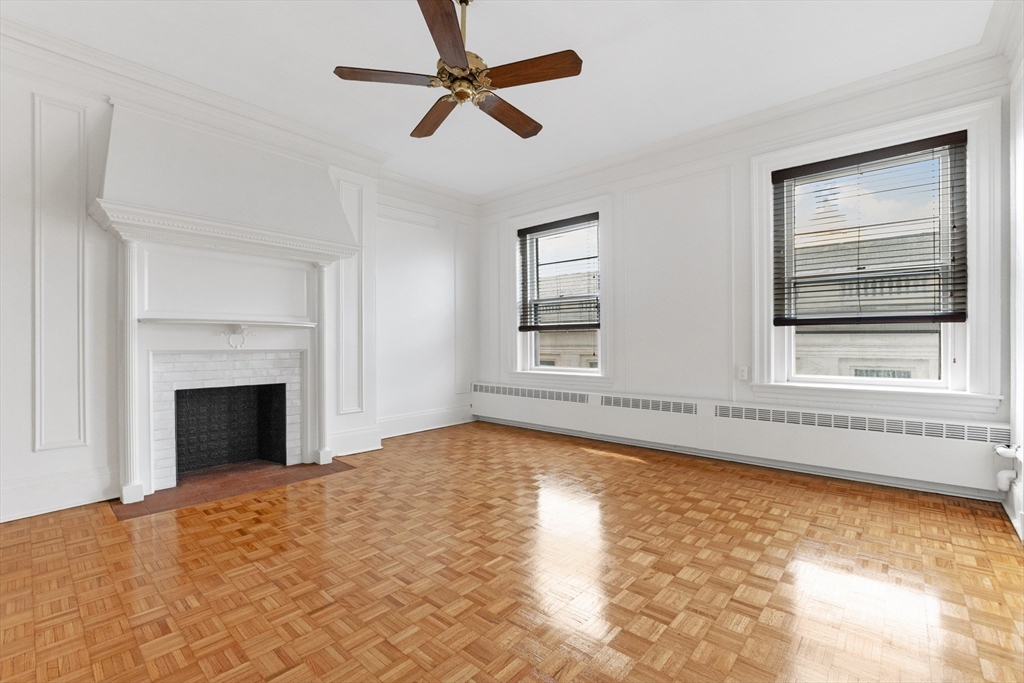 a view of an empty room with chandelier fan and fire place