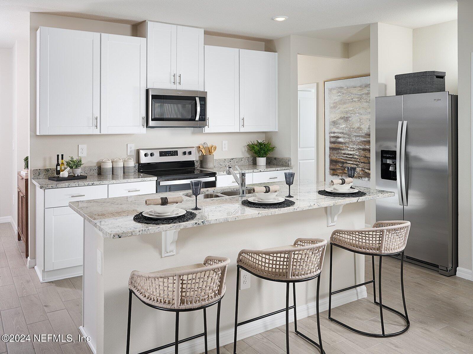 a kitchen with stainless steel appliances granite countertop a stove a sink a microwave and a refrigerator