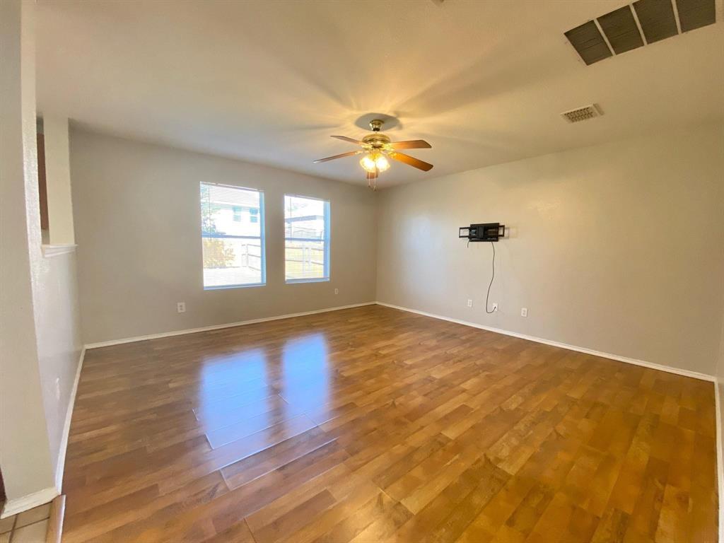 a view of an empty room with window and chandelier fan