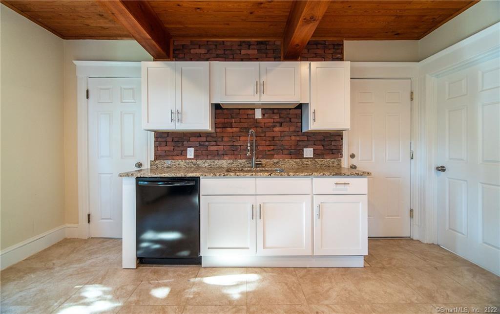 a kitchen with stainless steel appliances granite countertop a stove a sink and a refrigerator with white cabinets