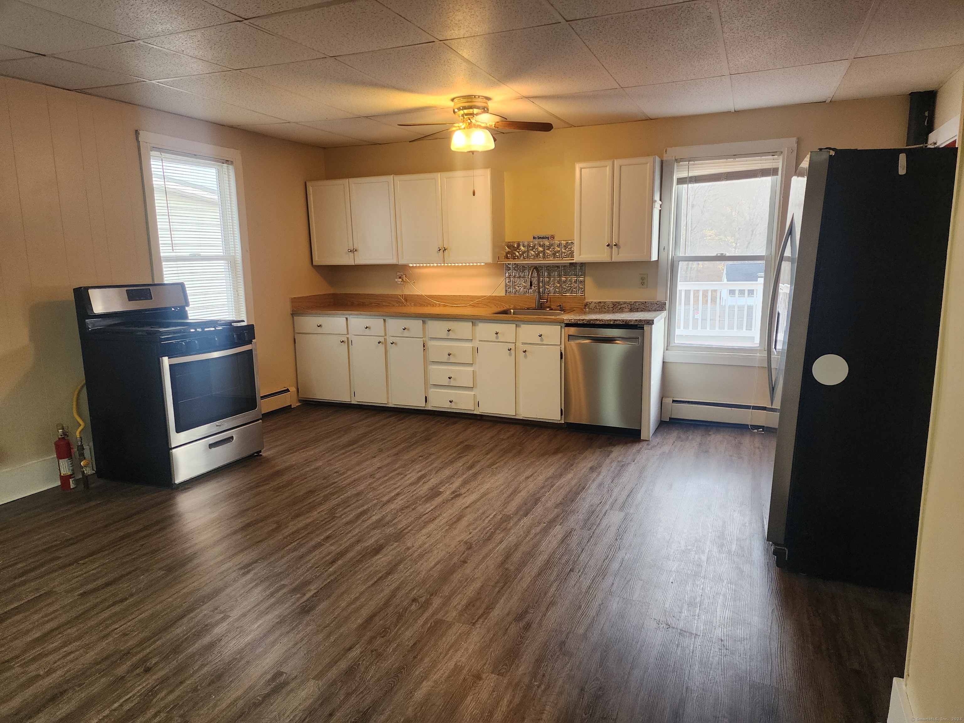 a kitchen with a refrigerator wooden floor a sink and a window