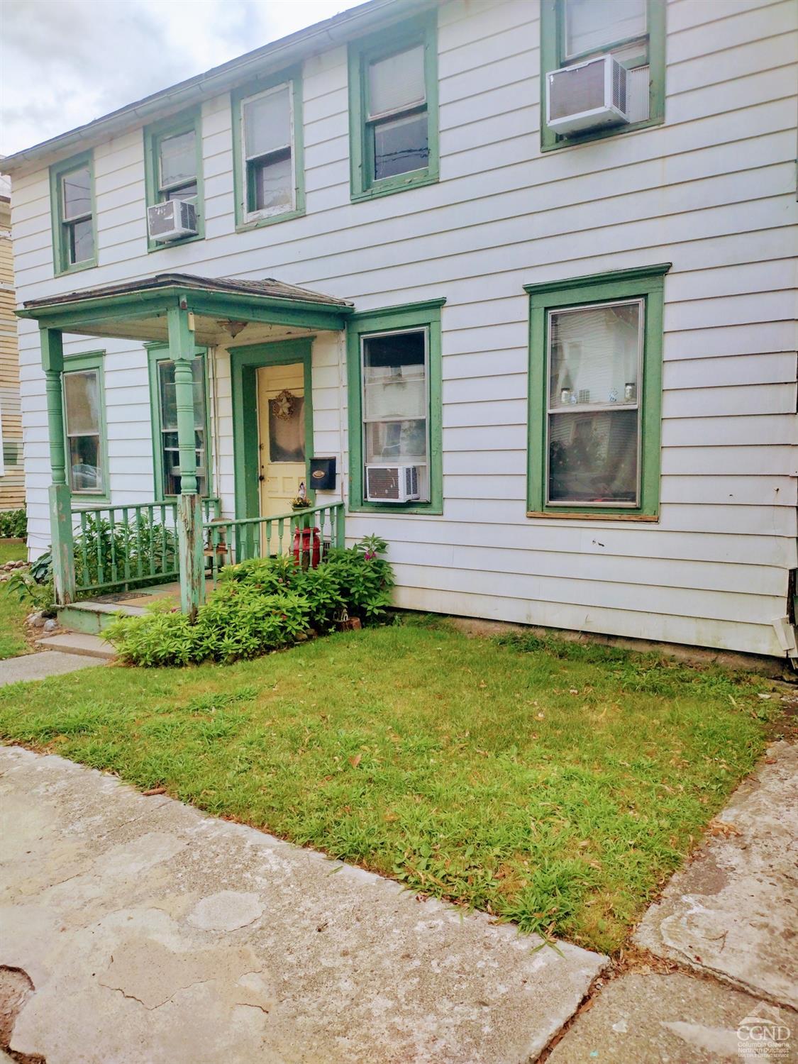 a view of a brick house with a yard potted plants and a table chair