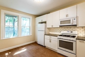 a kitchen with stainless steel appliances white cabinets and a stove top oven