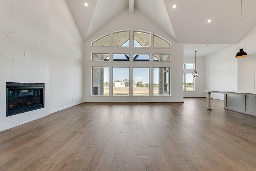 an empty room with wooden floor fireplace and windows