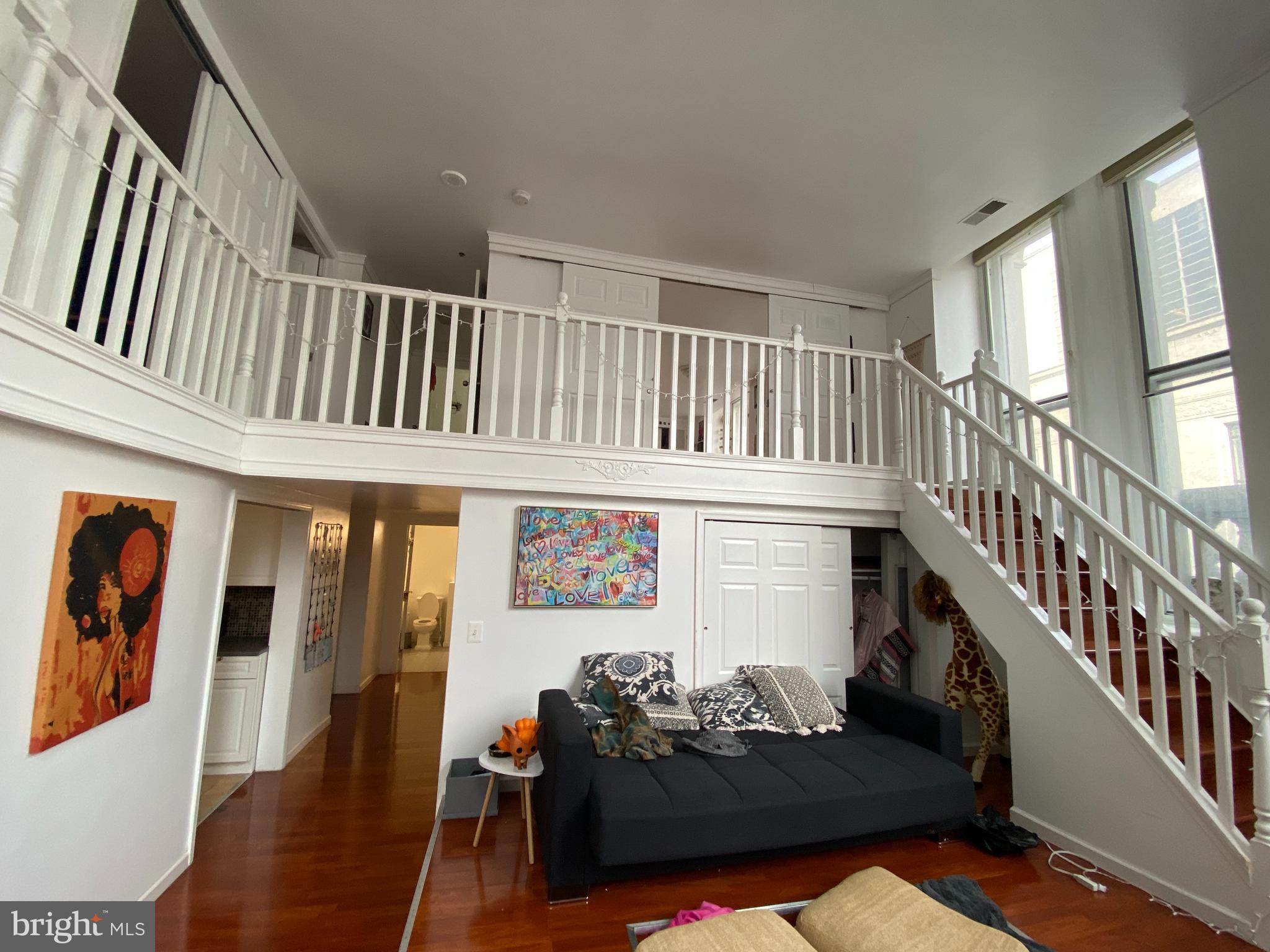 a living room with furniture stairs and a large window