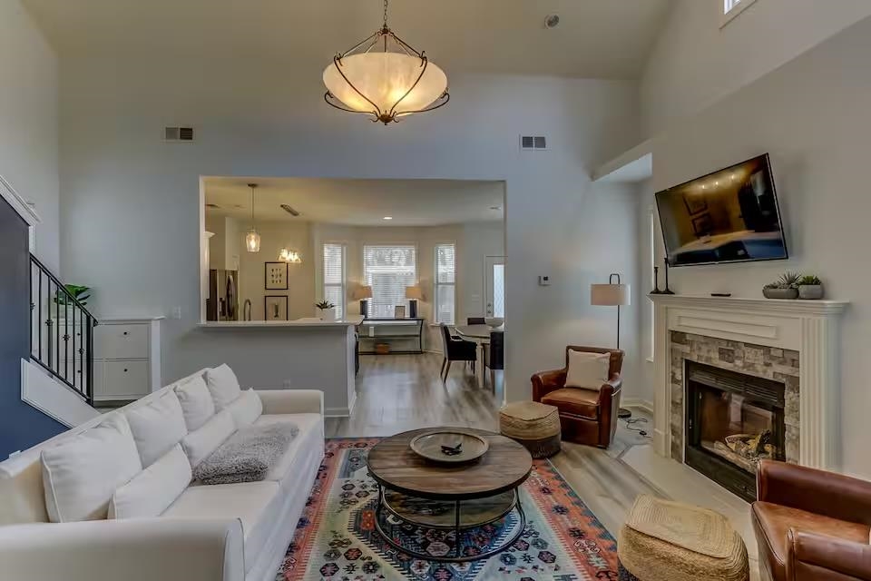 Living room featuring a fireplace, a towering ceiling, and light hardwood / wood-style floors