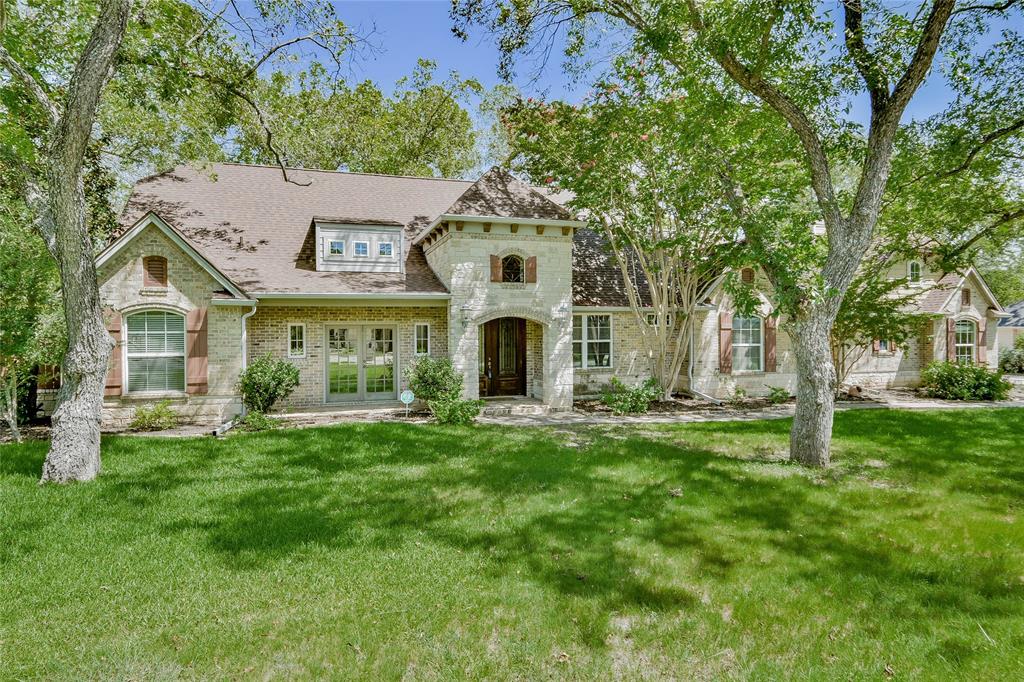 front view of a house with a big yard and large trees