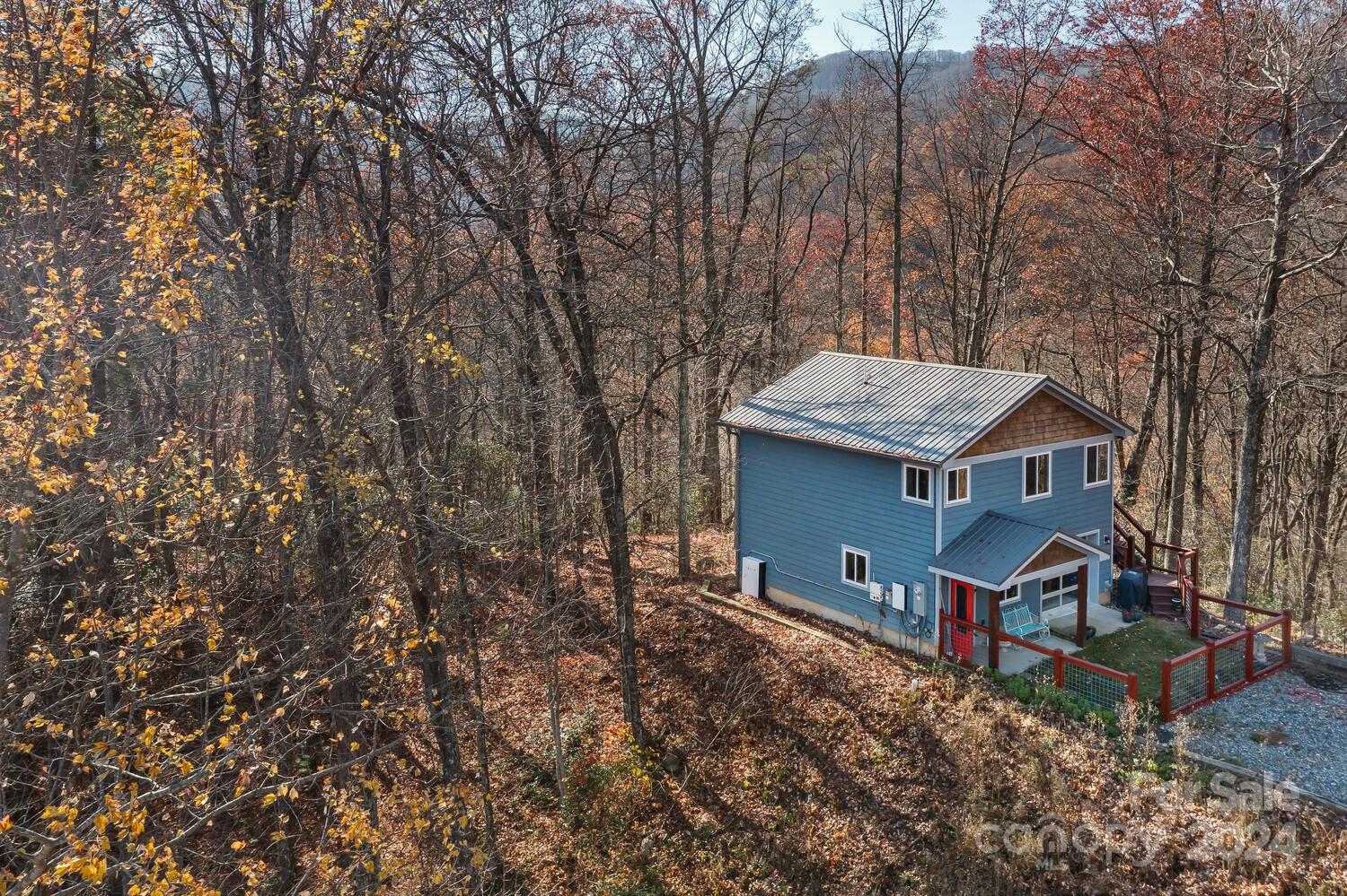 an aerial view of a house with yard and trees in the background