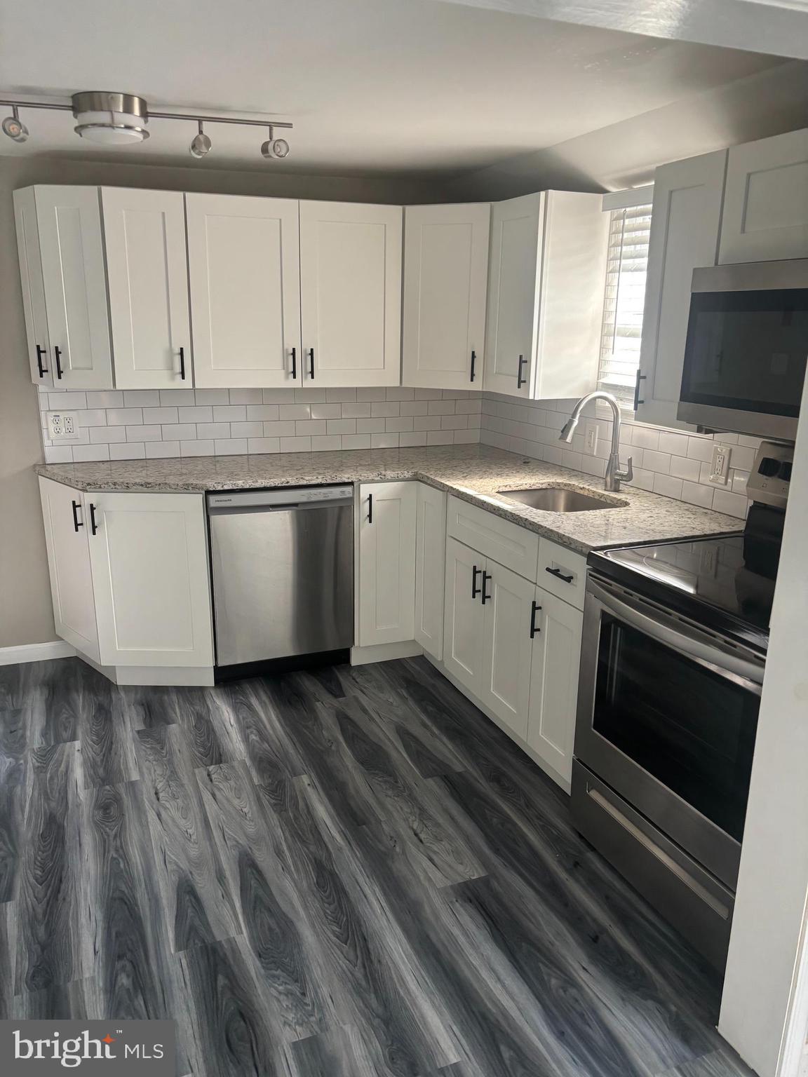 a kitchen with granite countertop a sink stainless steel appliances and cabinets