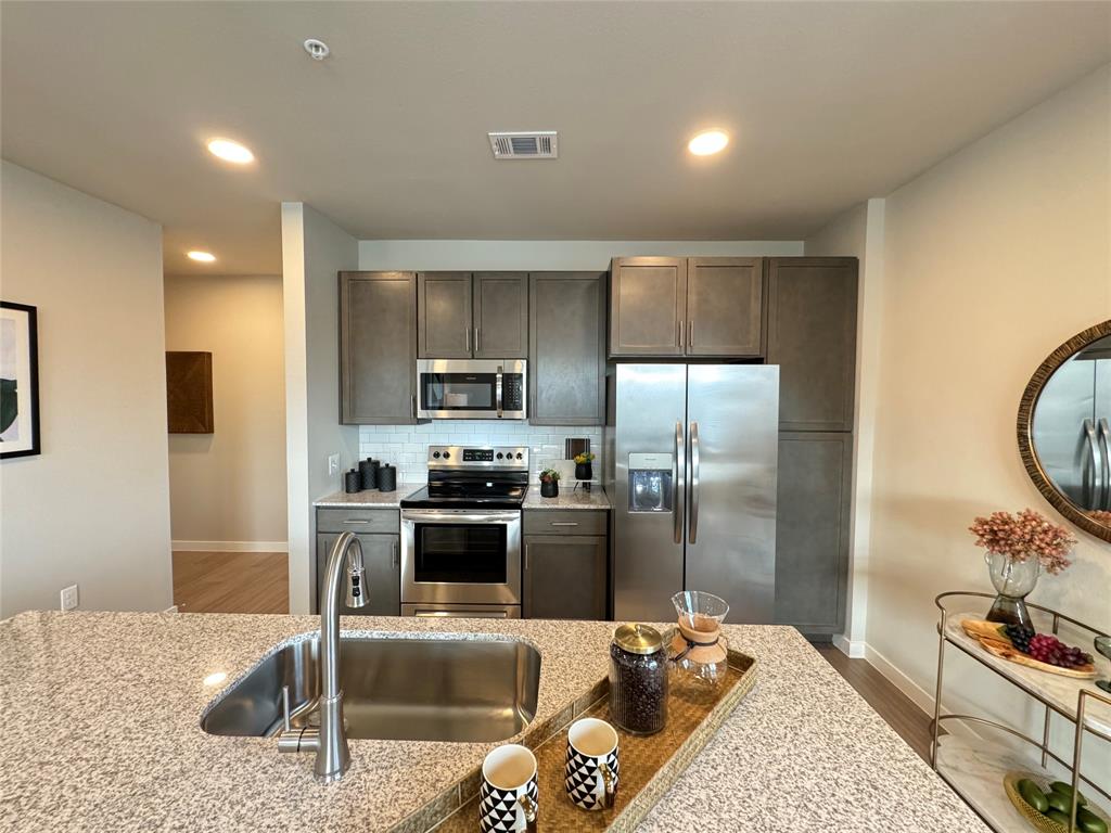 a kitchen with granite countertop a refrigerator and a stove top oven