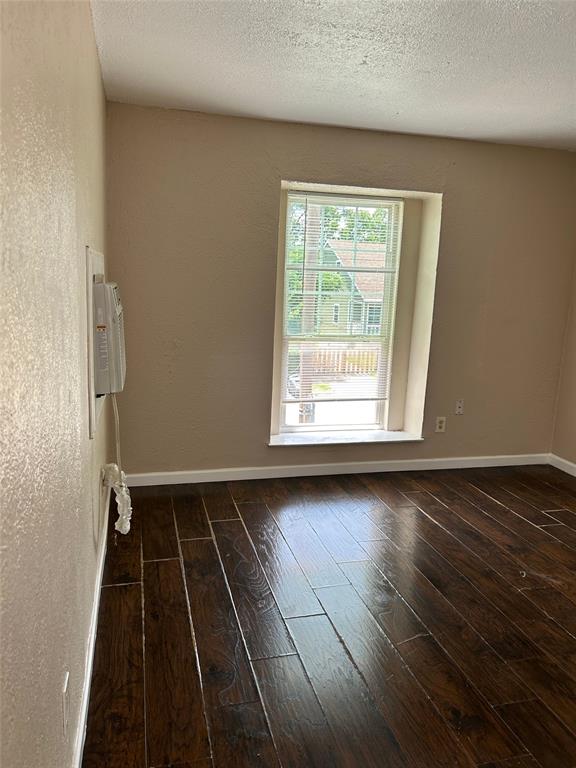 an empty room with wooden floor windows and exposed bricks