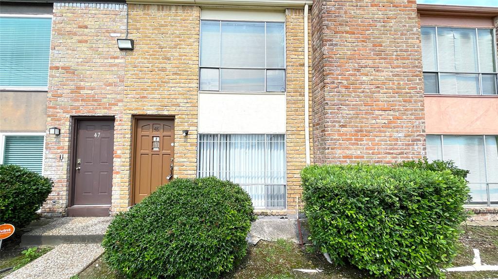 a brick house with a large windows and a potted plant