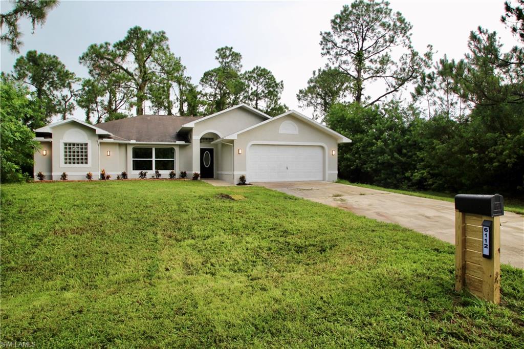 a front view of a house with a yard and trees