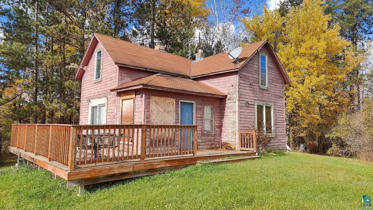 Back of house with a wooden deck and a lawn