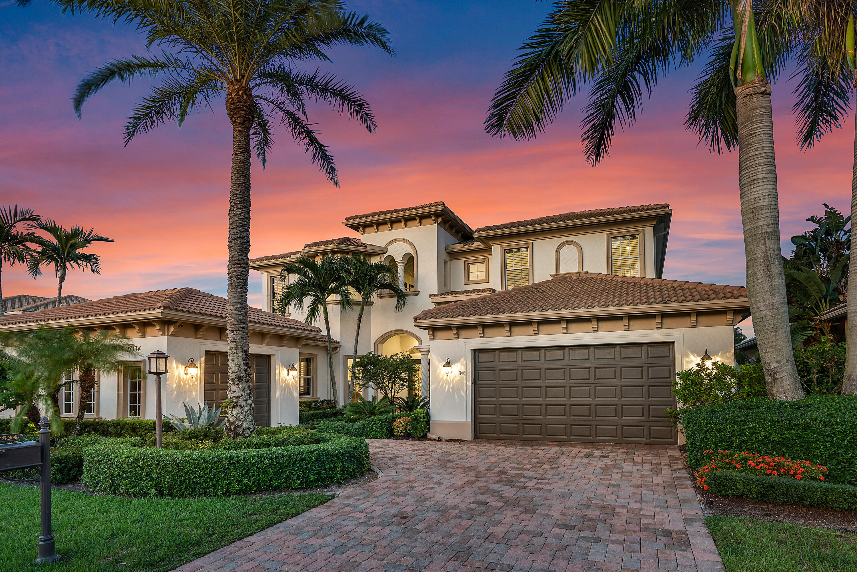 a front view of a house with a yard and palm trees