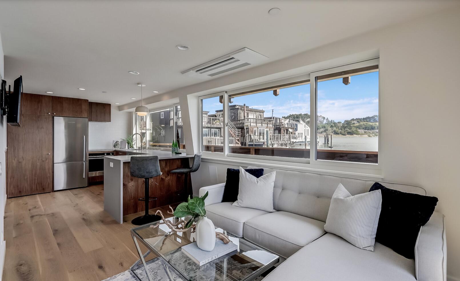 a living room with furniture large windows and wooden floor