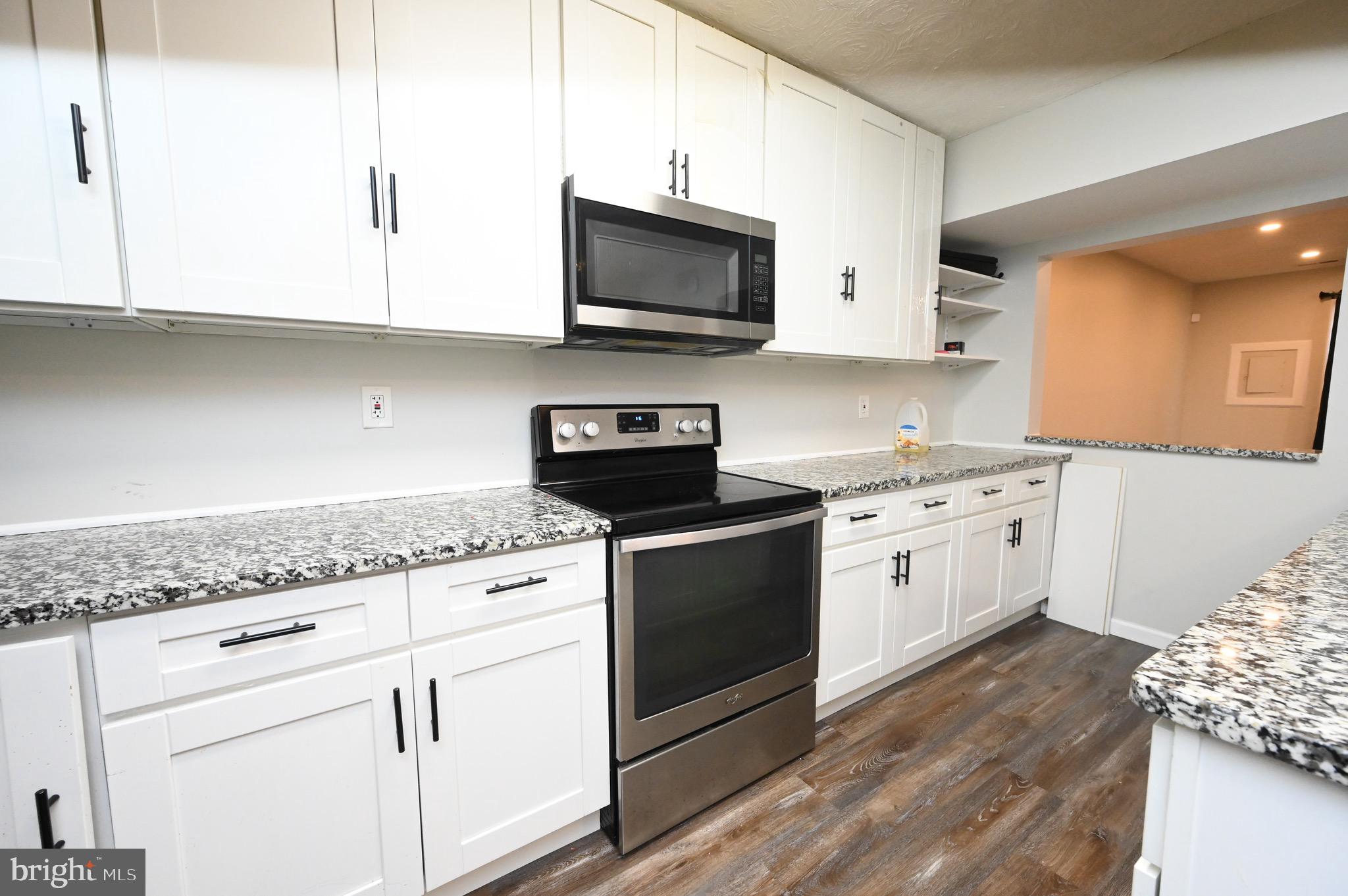 a kitchen with granite countertop white cabinets and white appliances