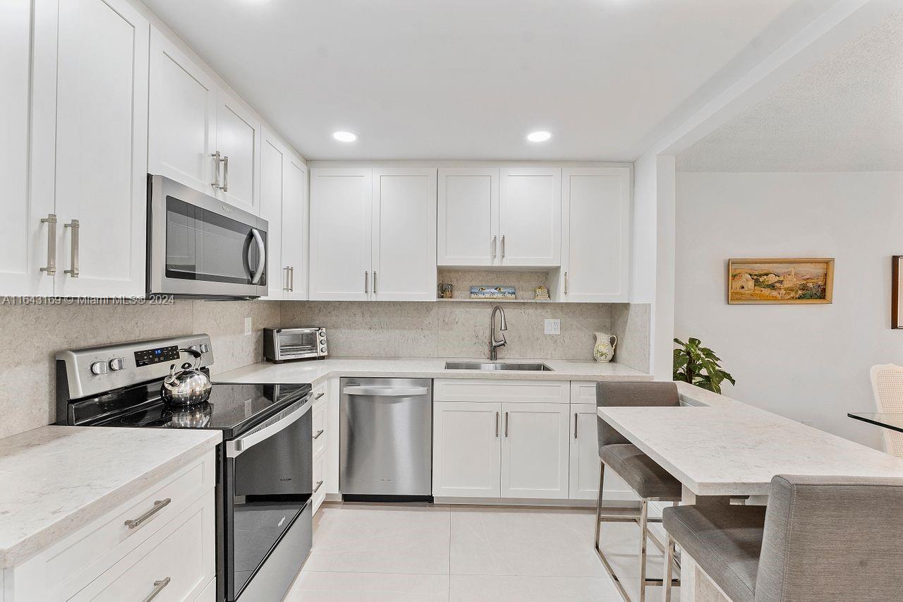 a kitchen with cabinets appliances a sink and a counter top space