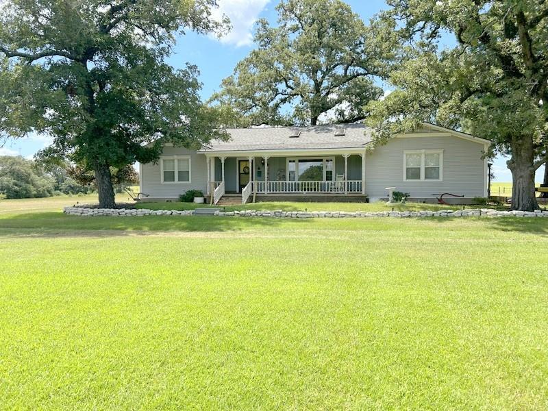 a view of a house with a big yard and large trees