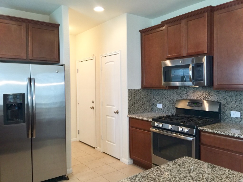 a kitchen with stainless steel appliances granite countertop a refrigerator and a stove top oven