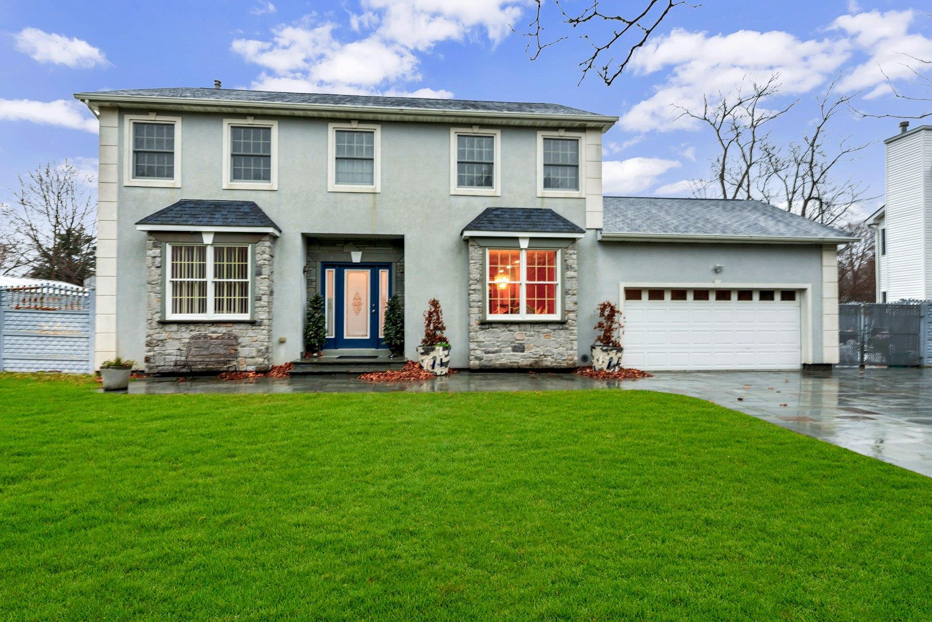 View of front of property featuring a garage and a front lawn