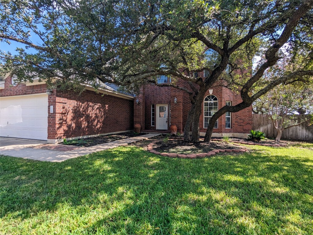 a front view of a house with garden and tree