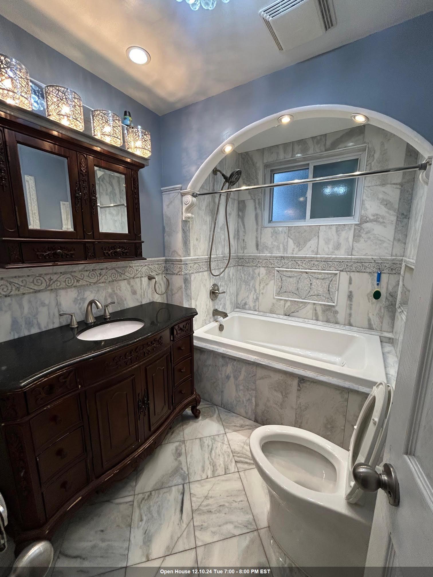 a spacious bathroom with a granite countertop sink a large mirror and bathtub