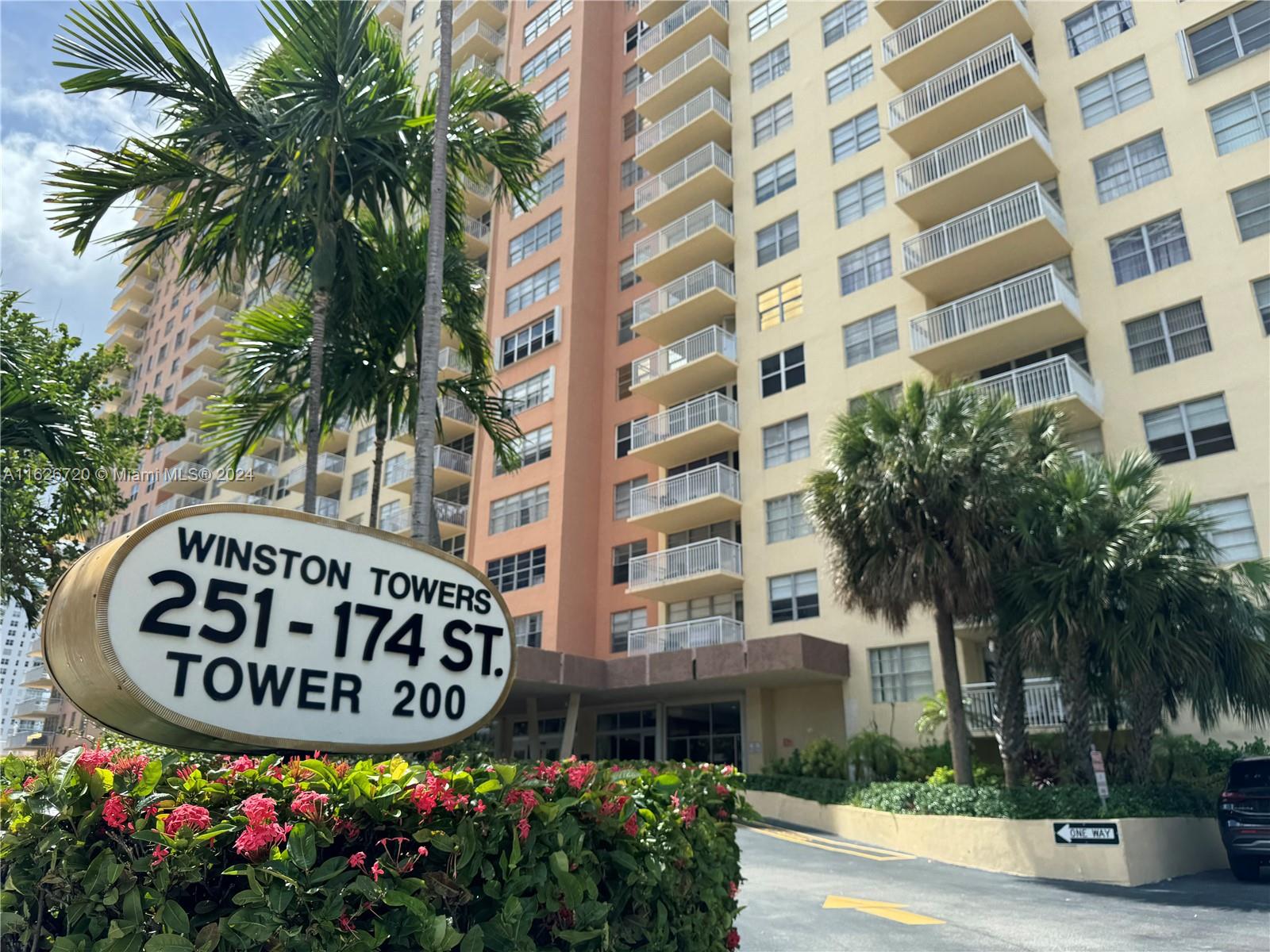 a front view of multi story residential apartment building with yard and sign board