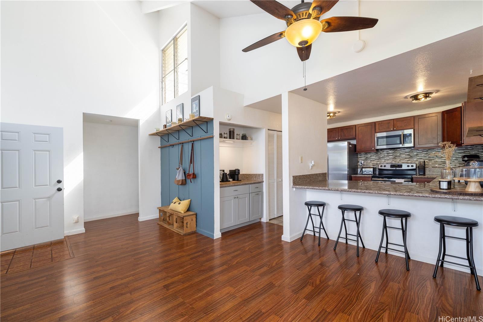 a view of a kitchen with furniture a ceiling fan and wooden floor