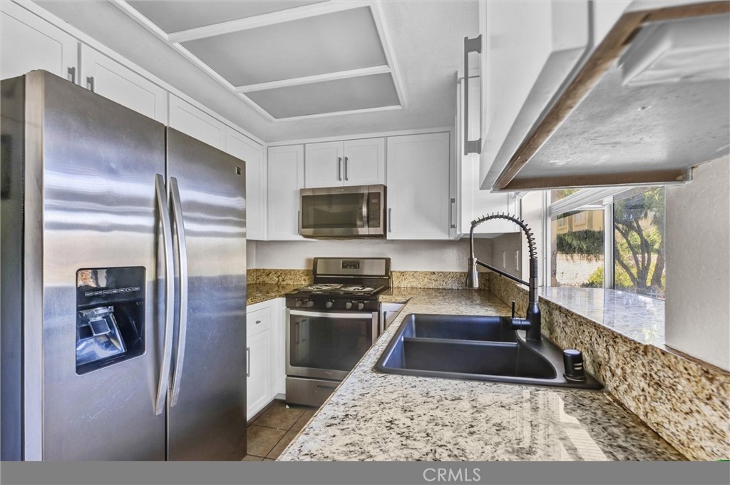 a kitchen with stainless steel appliances granite countertop a refrigerator a stove top oven a sink and dishwasher