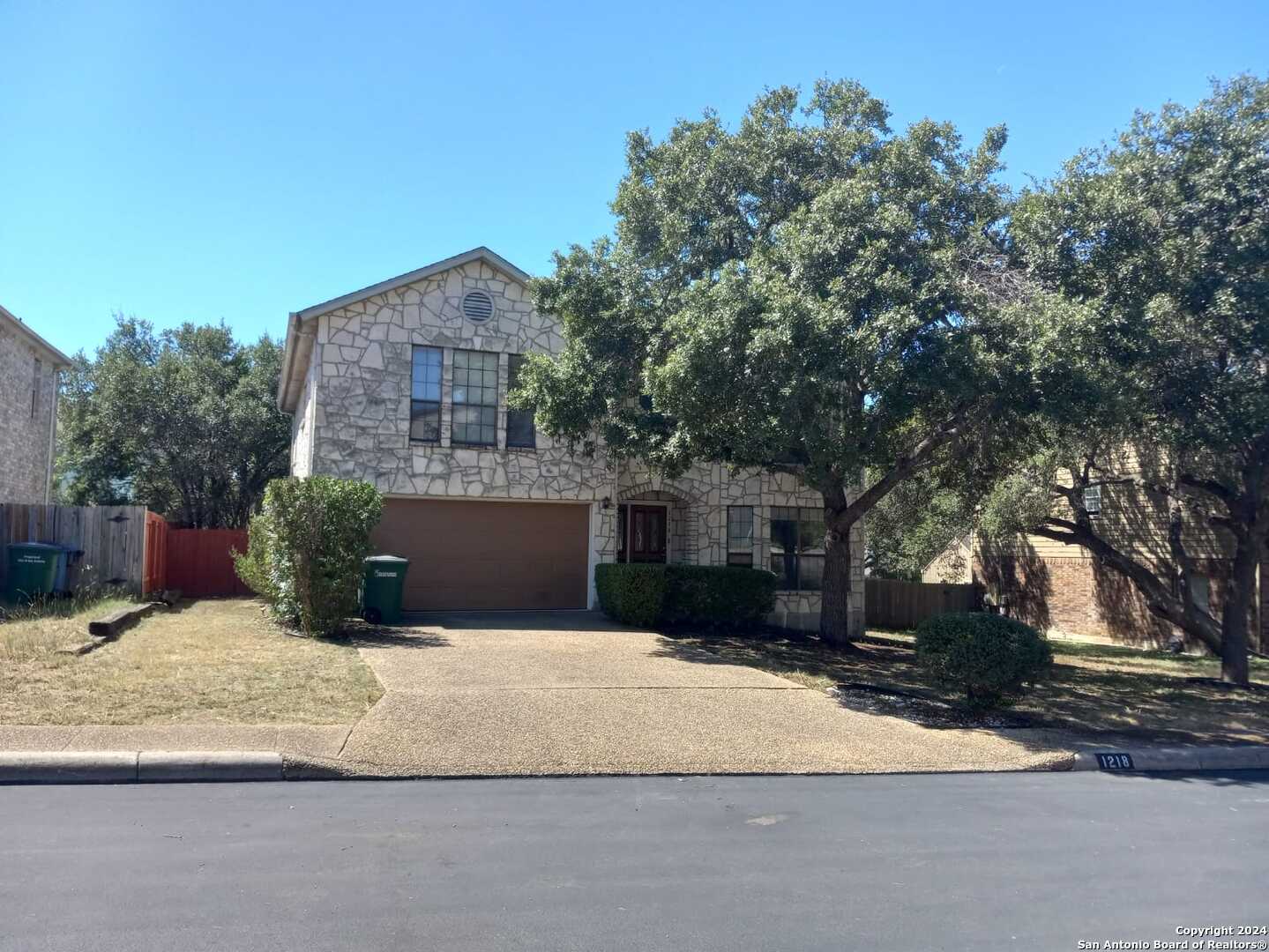 a view of a house with a yard and a large tree