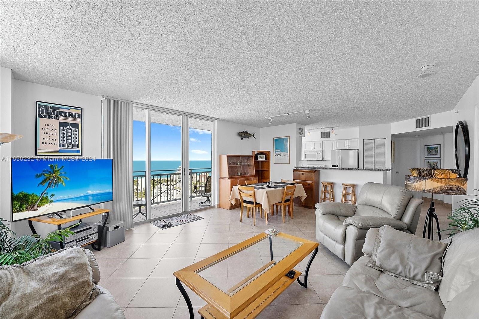 a living room with furniture a flat screen tv and floor to ceiling window