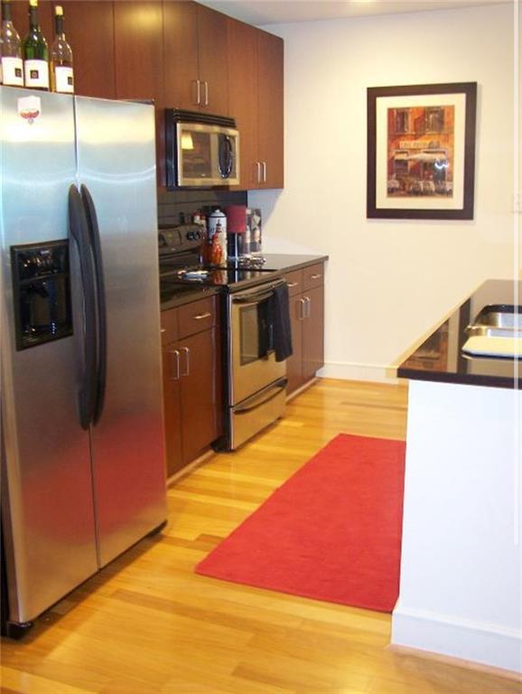 a kitchen with stainless steel appliances granite countertop a refrigerator a stove and a sink