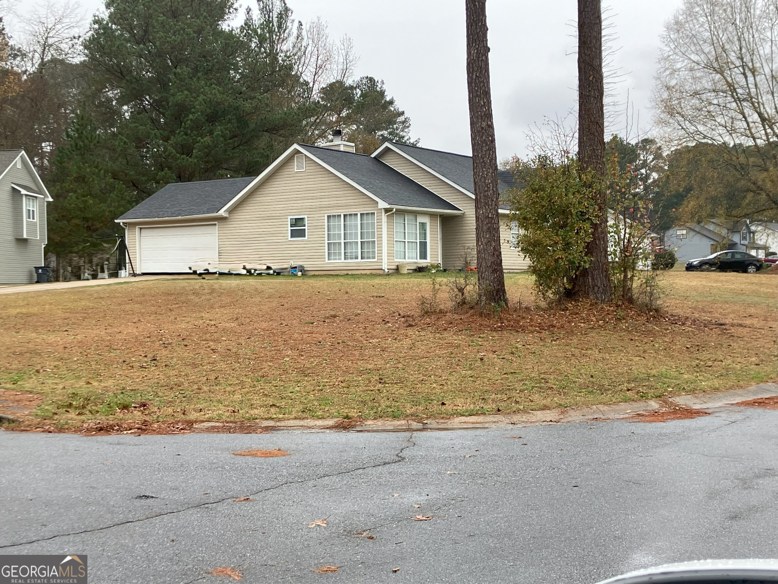 a view of house with a yard and large trees