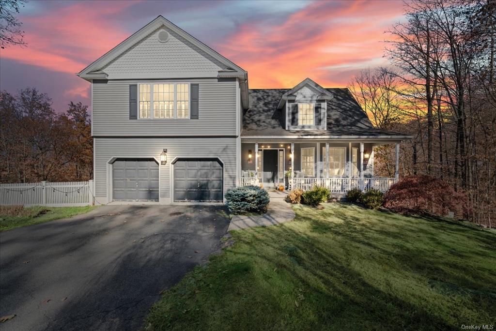 View of front of house featuring a lawn, a porch, and a garage