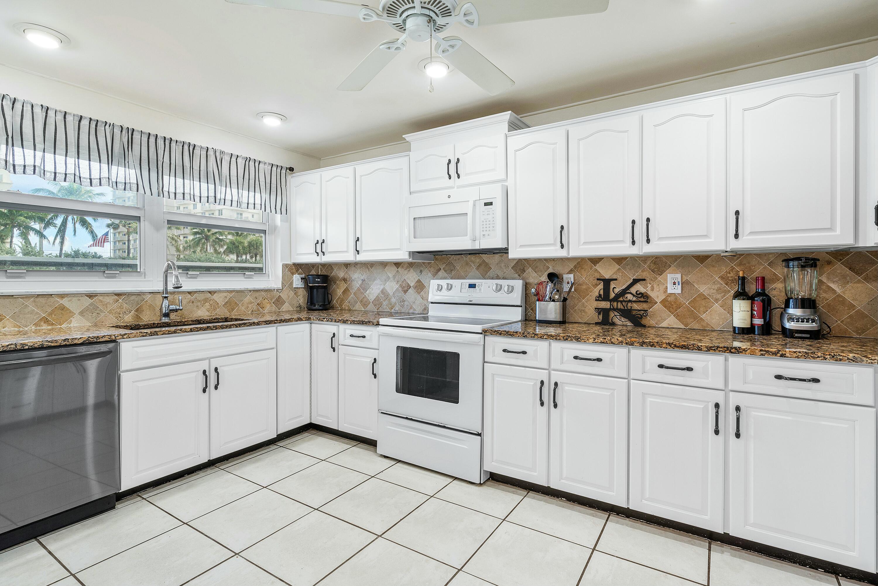 a kitchen with granite countertop white cabinets stainless steel appliances a sink and dishwasher